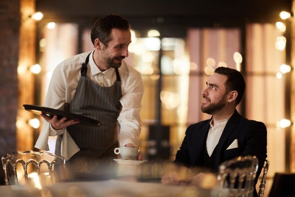 Kellner serviert einem Gast einen Kaffee in einem noblen Restaurant