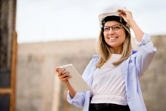 Bauherrin auf der Baustelle mit Bauhelm und Tablet