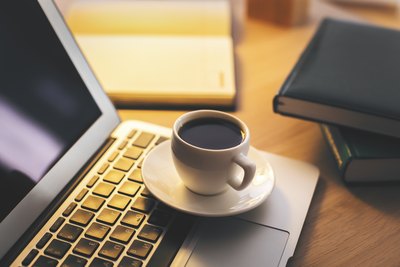 Morgendliche Kaffeetasse steht auf einem Laptop