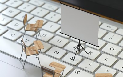 Tastatur auf der drei Miniatursesseln aus Holz stehen sowie eine weiße Schulungstafel